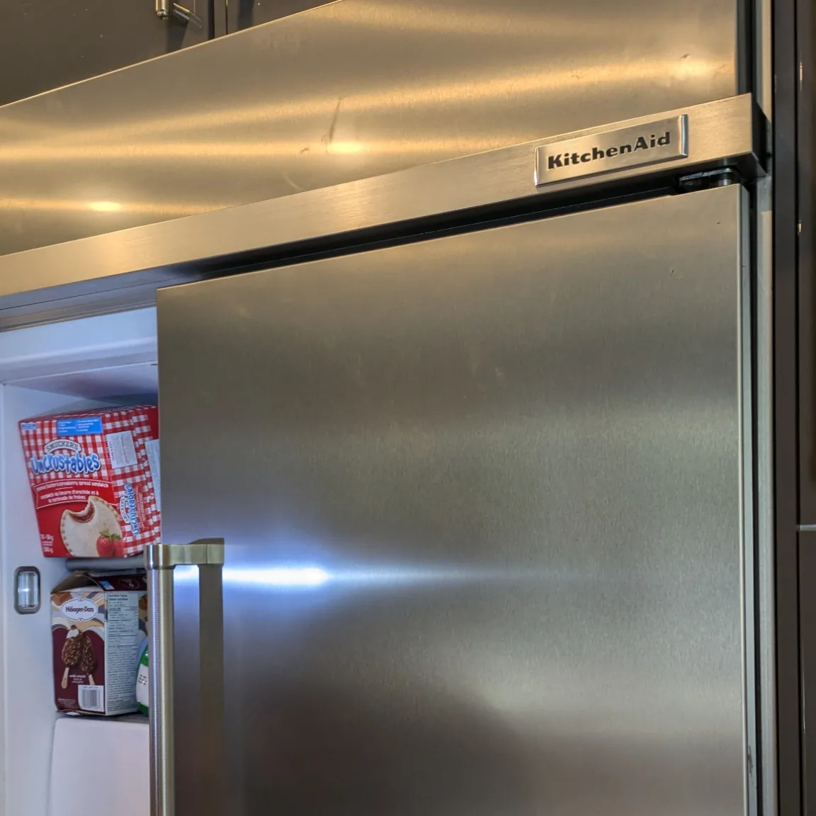 Technician inspecting a KitchenAid refrigerator